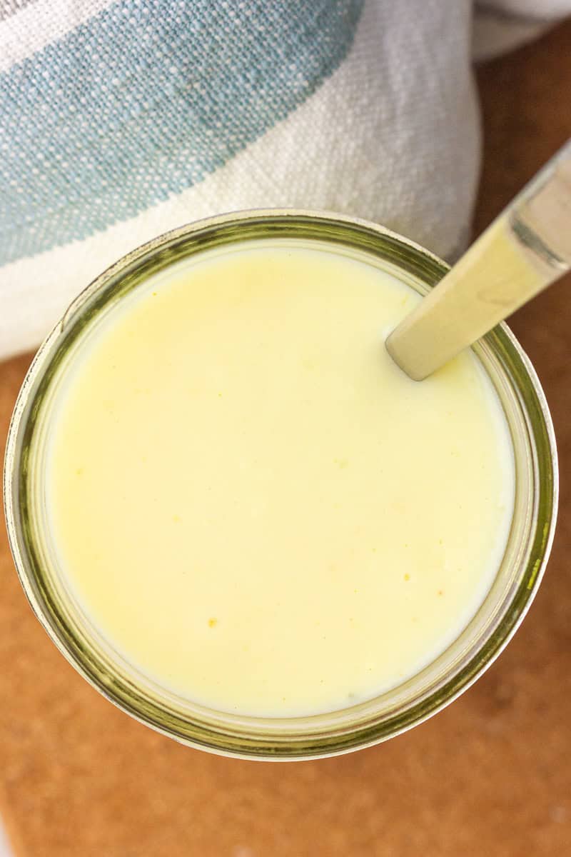 Top-down view of a jar of the creamy sauce with a spoon resting inside.