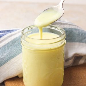 Close-up of a spoon pouring the creamy soup base into a mason jar for the featured image.