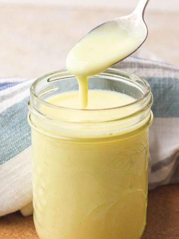 Close-up of a spoon pouring the creamy soup base into a mason jar for the featured image.