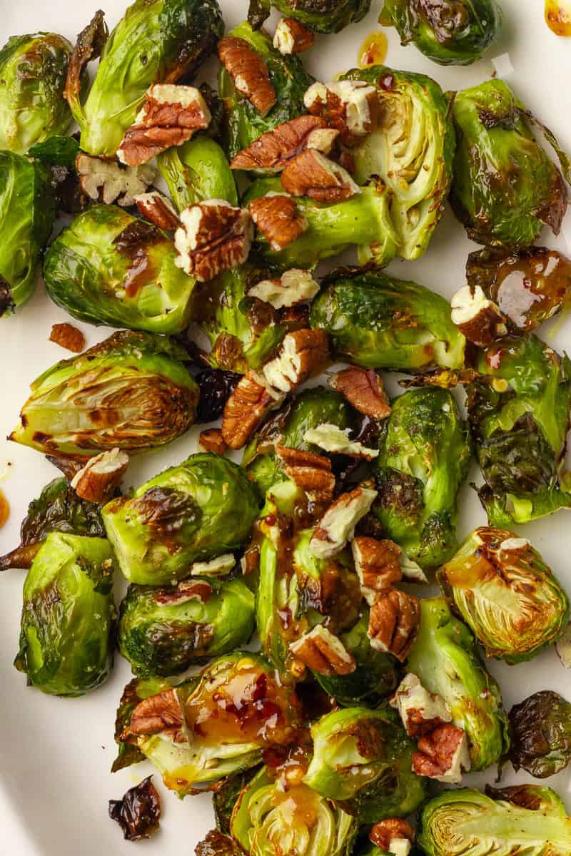 Close up of roasted Brussels sprouts coated in hot honey glaze and sprinkled with toasted pecans.