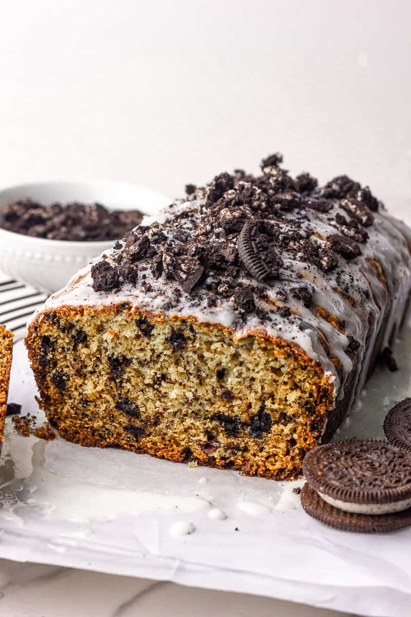 Close-up of the glazed loaf with the end sliced and Oreo crumbs scattered.