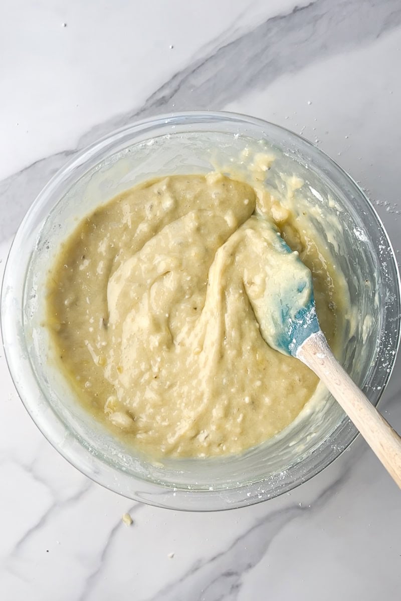 Smooth banana bread batter in a glass bowl with a spatula.