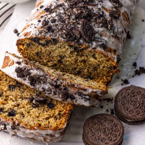 Glazed Oreo banana bread topped with crushed cookies, sliced to show the cookie-studded crumb.