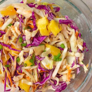 An overhead shot features vibrant pineapple slaw in a clear bowl ready to serve.