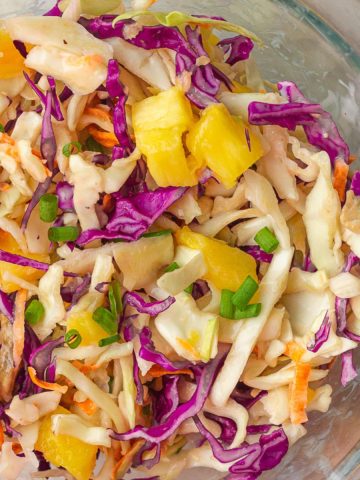 An overhead shot features vibrant pineapple slaw in a clear bowl ready to serve.