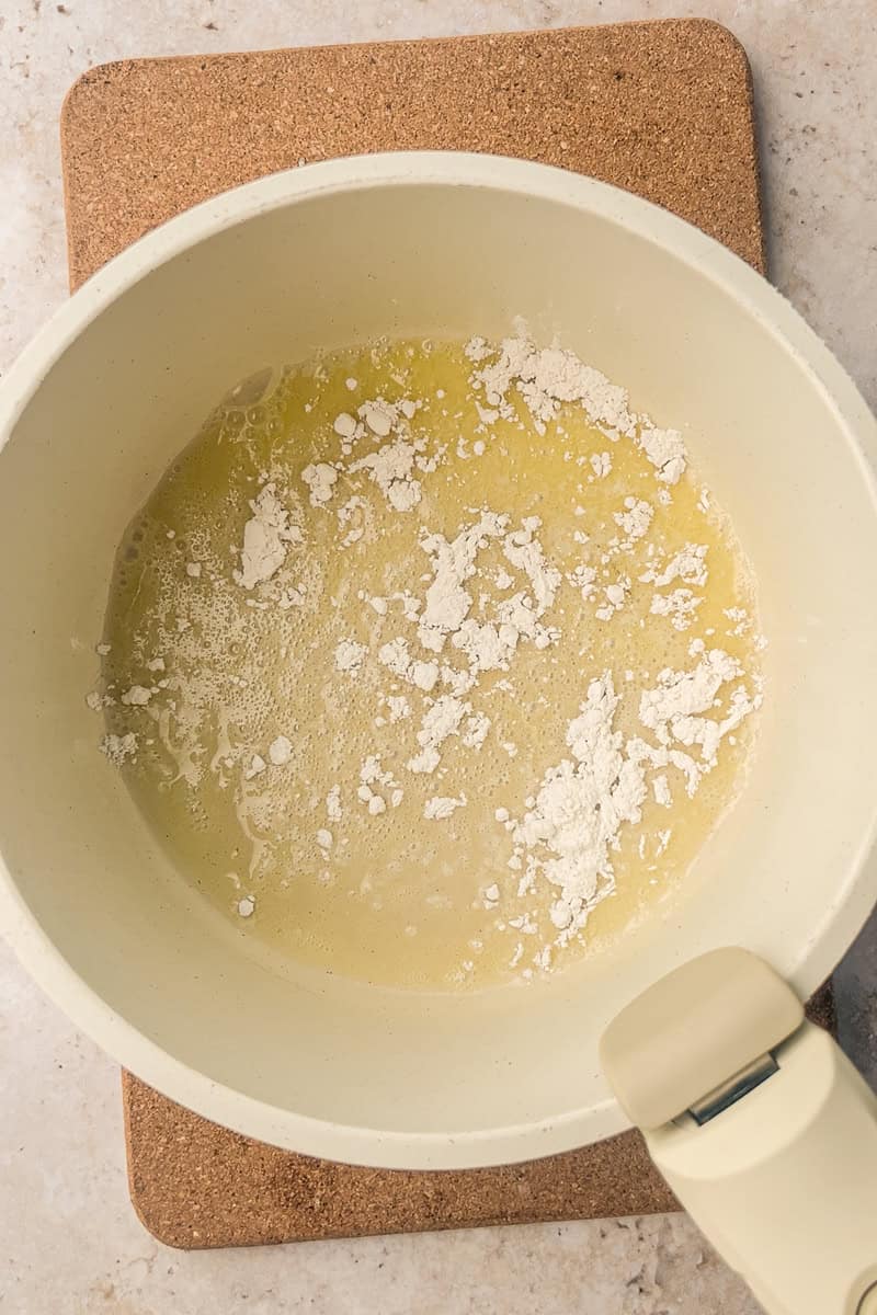 Butter and flour being cooked together in a saucepan to form a roux.