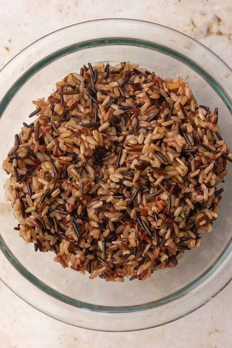 A clear glass bowl holds cooked wild rice in a close-up overhead shot.