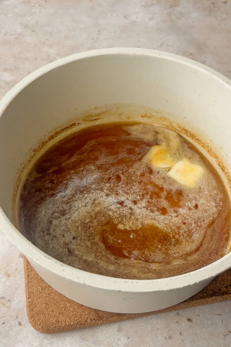 Butter melts into reduced apple cider and sugar in a saucepan as the caramel gently simmers.
