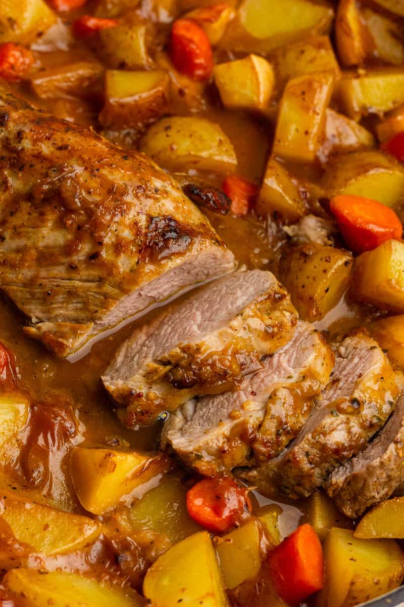 Close-up of juicy apple cider pork tenderloin with tender carrots and golden potatoes.