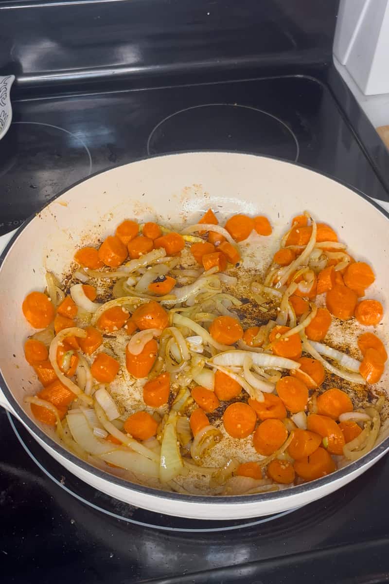 Onions and carrots sautéing in a pan as the base for apple cider pork tenderloin.