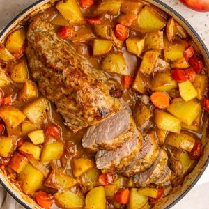 Overhead view of apple cider pork tenderloin surrounded by roasted potatoes and carrots.