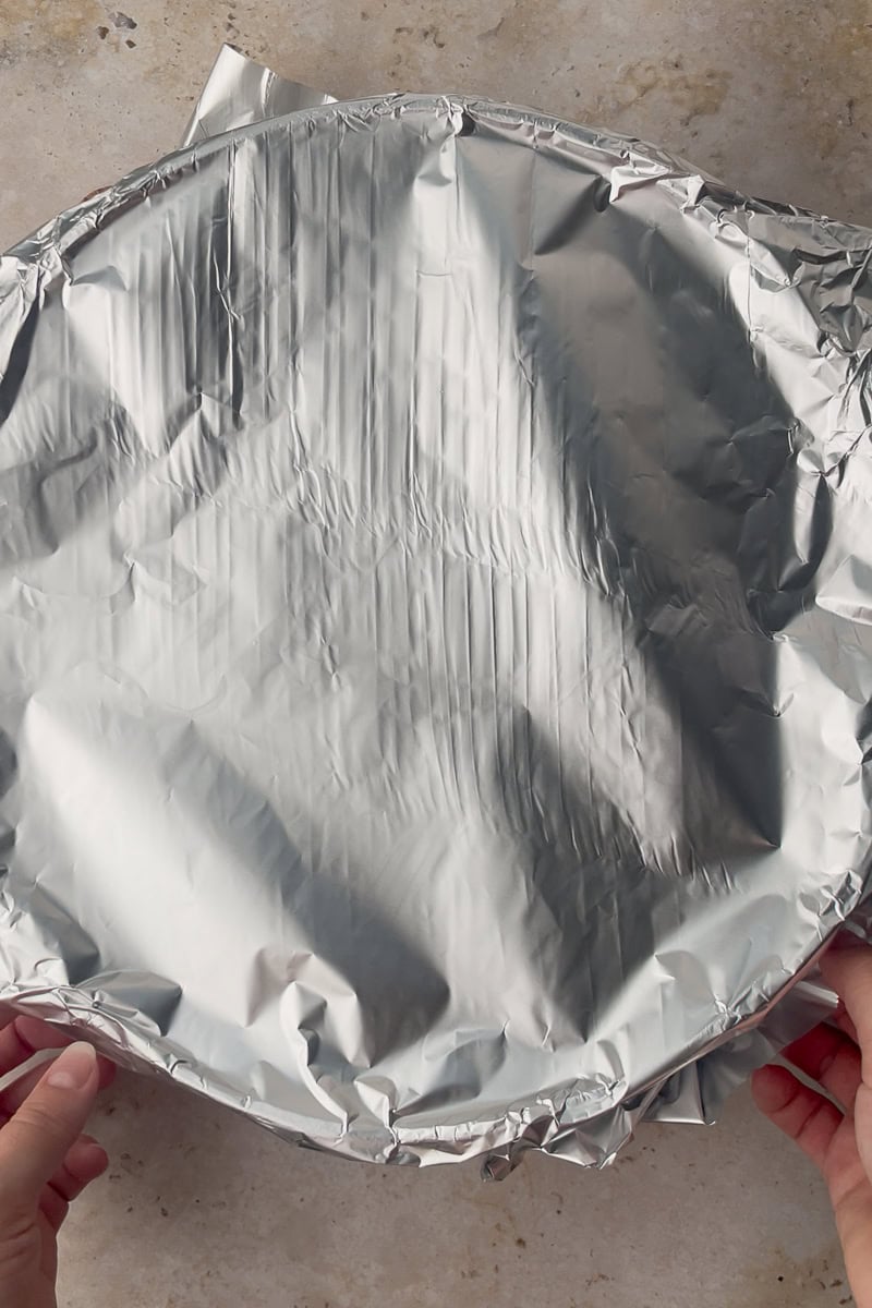 The oven-safe skillet is tightly covered with aluminum foil before baking.
