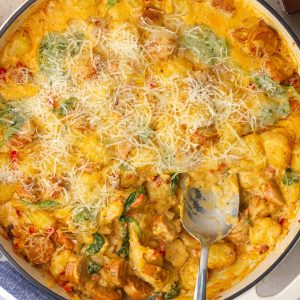 The finished Cajun gnocchi skillet is golden and cheesy with a portion scooped out to show the creamy interior.
