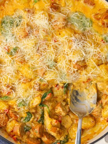 The finished Cajun gnocchi skillet is golden and cheesy with a portion scooped out to show the creamy interior.