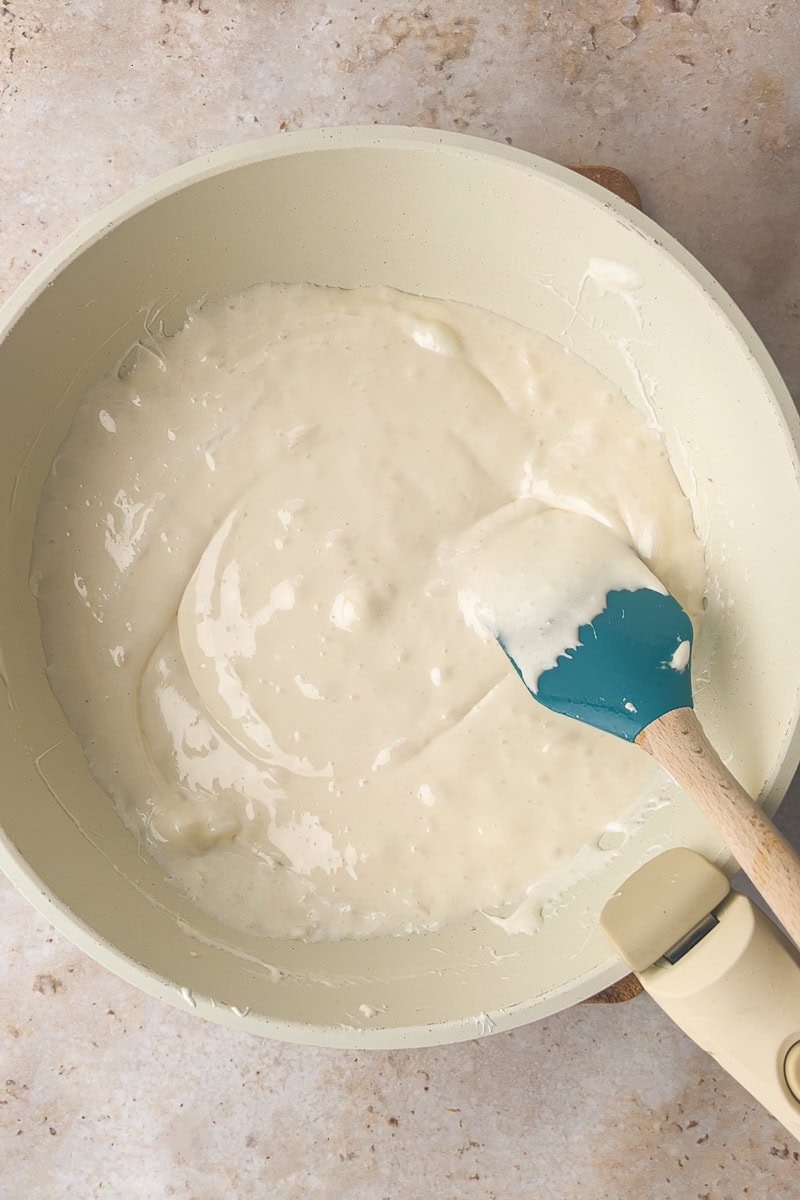 Melted marshmallows and butter are stirred in a saucepan with a spatula.