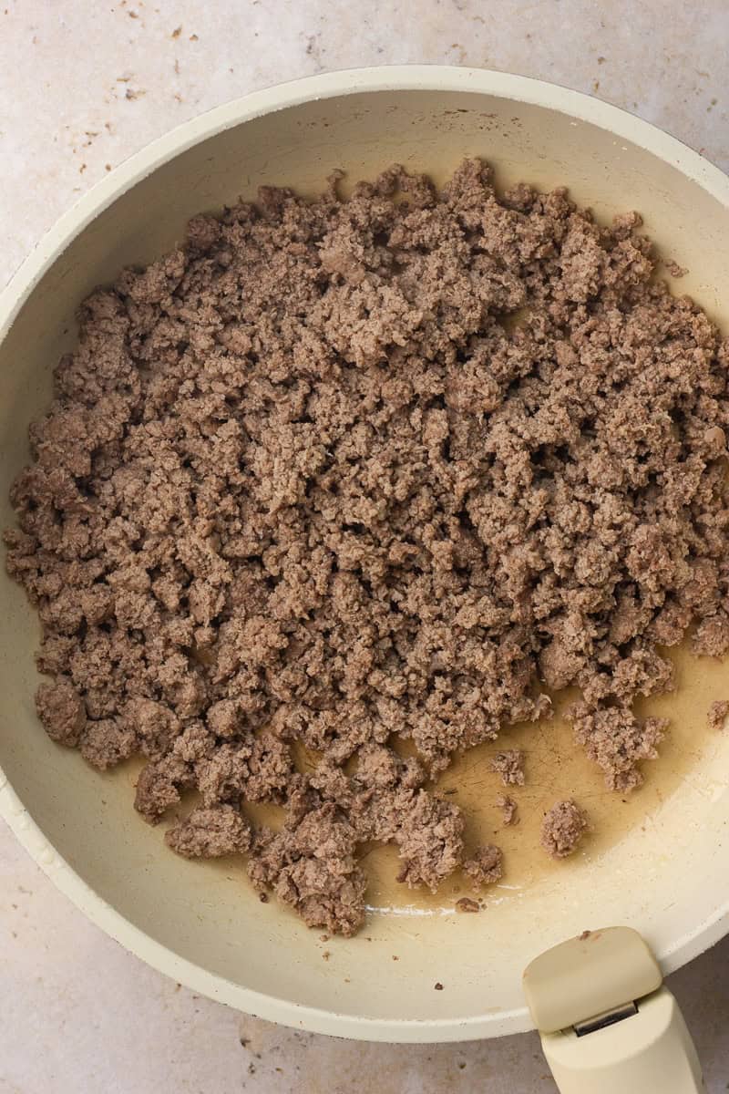 A skillet is filled with browned, crumbled ground turkey ready for the slow cooker.