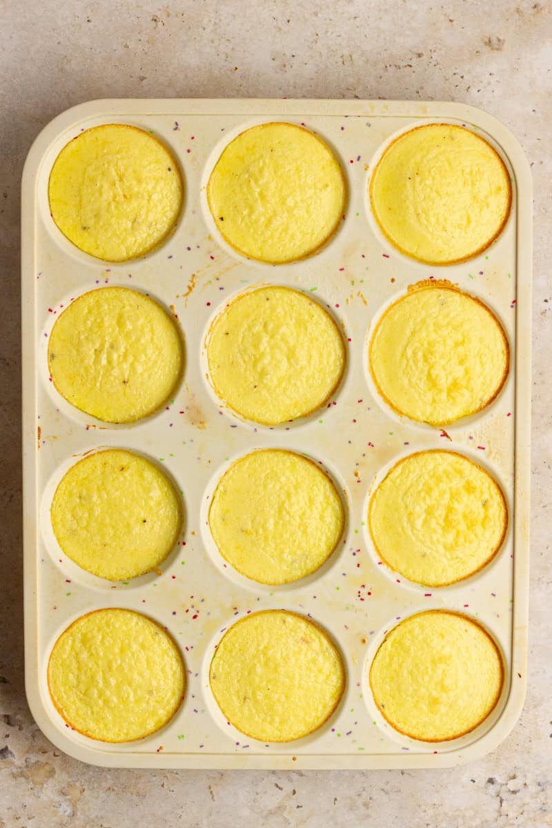 A muffin tin filled with freshly baked ham and cheese egg bites cooling on the counter.
