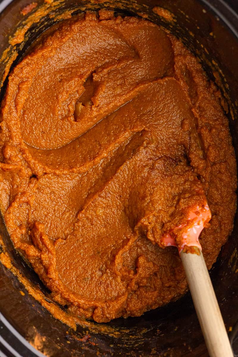 Thick and smooth apple pumpkin butter being stirred in a slow cooker after cooking.