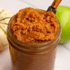 Close-up of a jar filled with pumpkin apple butter showing its thick, rich texture.