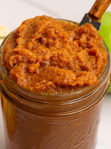 Close-up of a jar filled with pumpkin apple butter showing its thick, rich texture.