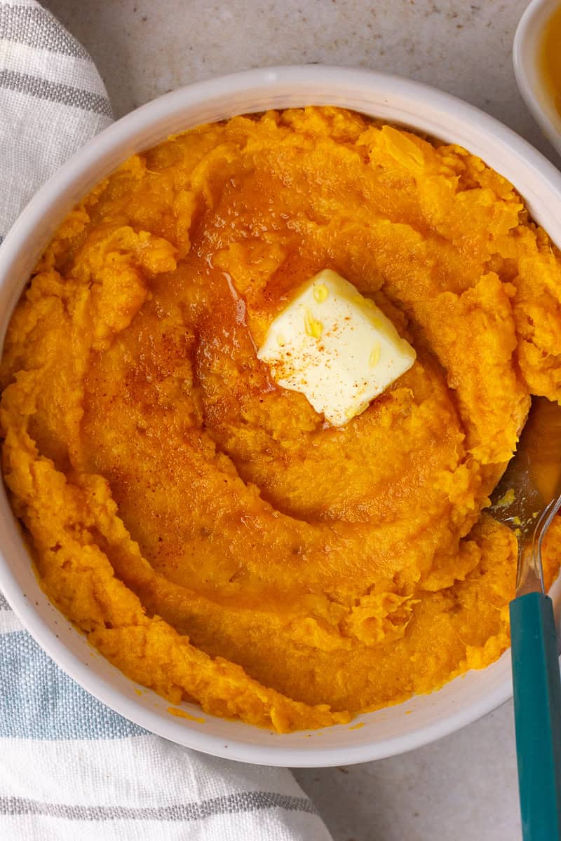 Creamy mashed sweet potatoes topped with a pat of butter and drizzle of hot honey.