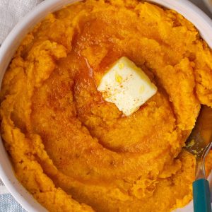 Close-up of spicy mashed sweet potatoes with melted butter and a sprinkle of paprika.