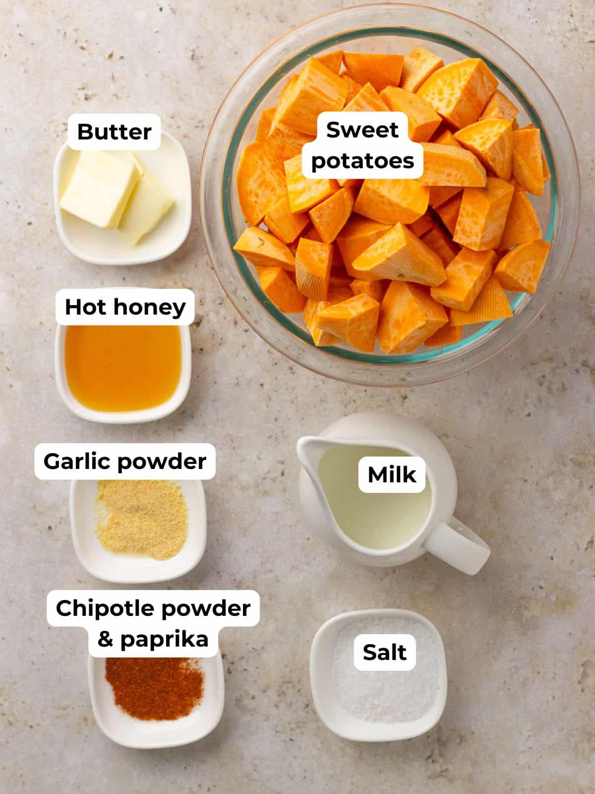 Overhead shot of labeled ingredients for spicy mashed sweet potatoes, including sweet potatoes, butter, hot honey, milk, and spices.