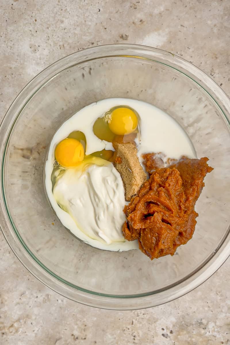 Bowl filled with Greek yogurt, eggs, milk, brown sugar, and apple butter before mixing.