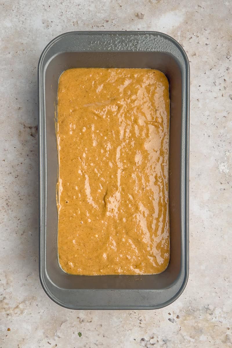 Batter for apple butter bread poured evenly into a greased loaf pan ready to bake.