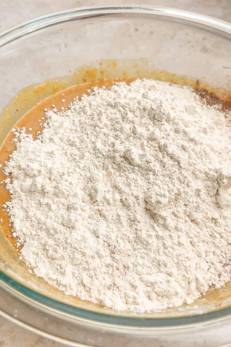 Mixing dry ingredients like flour, cinnamon, and nutmeg into the wet apple butter batter.