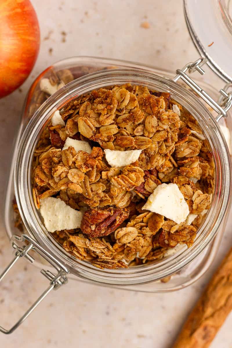 Overhead view of apple crumble granola in a jar showing large clusters and pieces of freeze-dried apples.