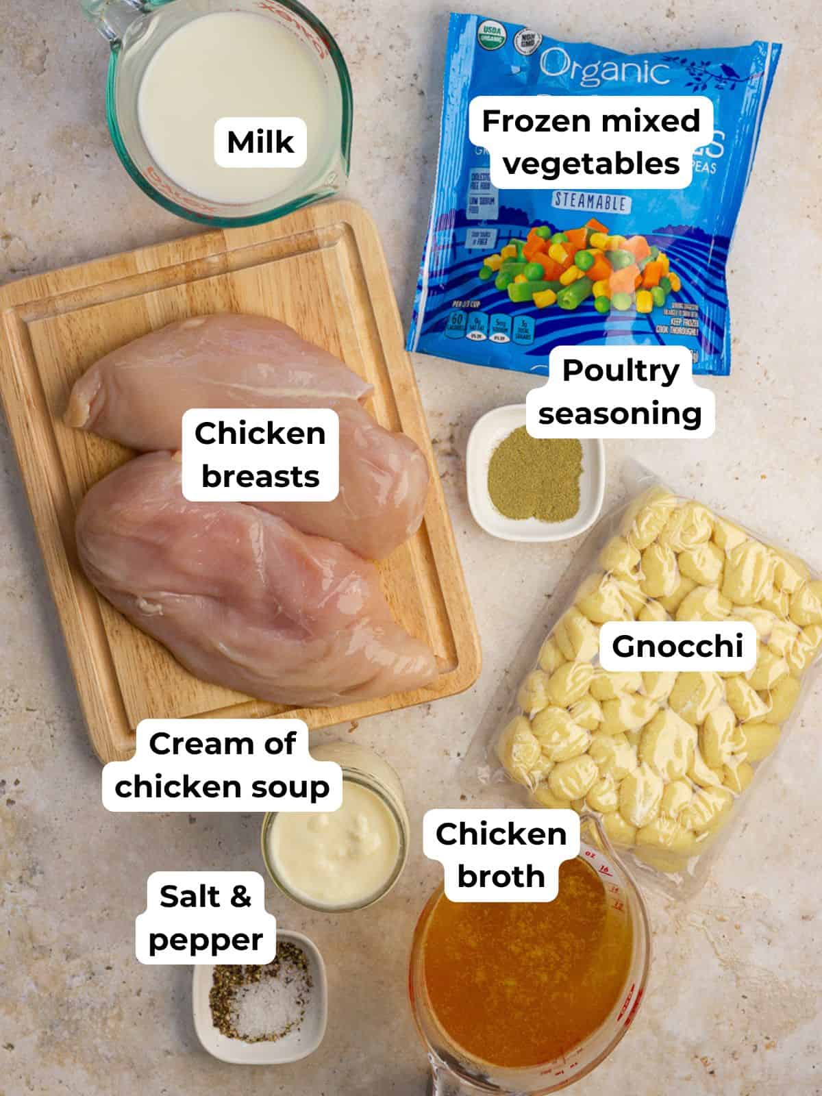 All ingredients for chicken pot pie gnocchi soup are laid out, including chicken, broth, milk, veggies, gnocchi, and seasonings.