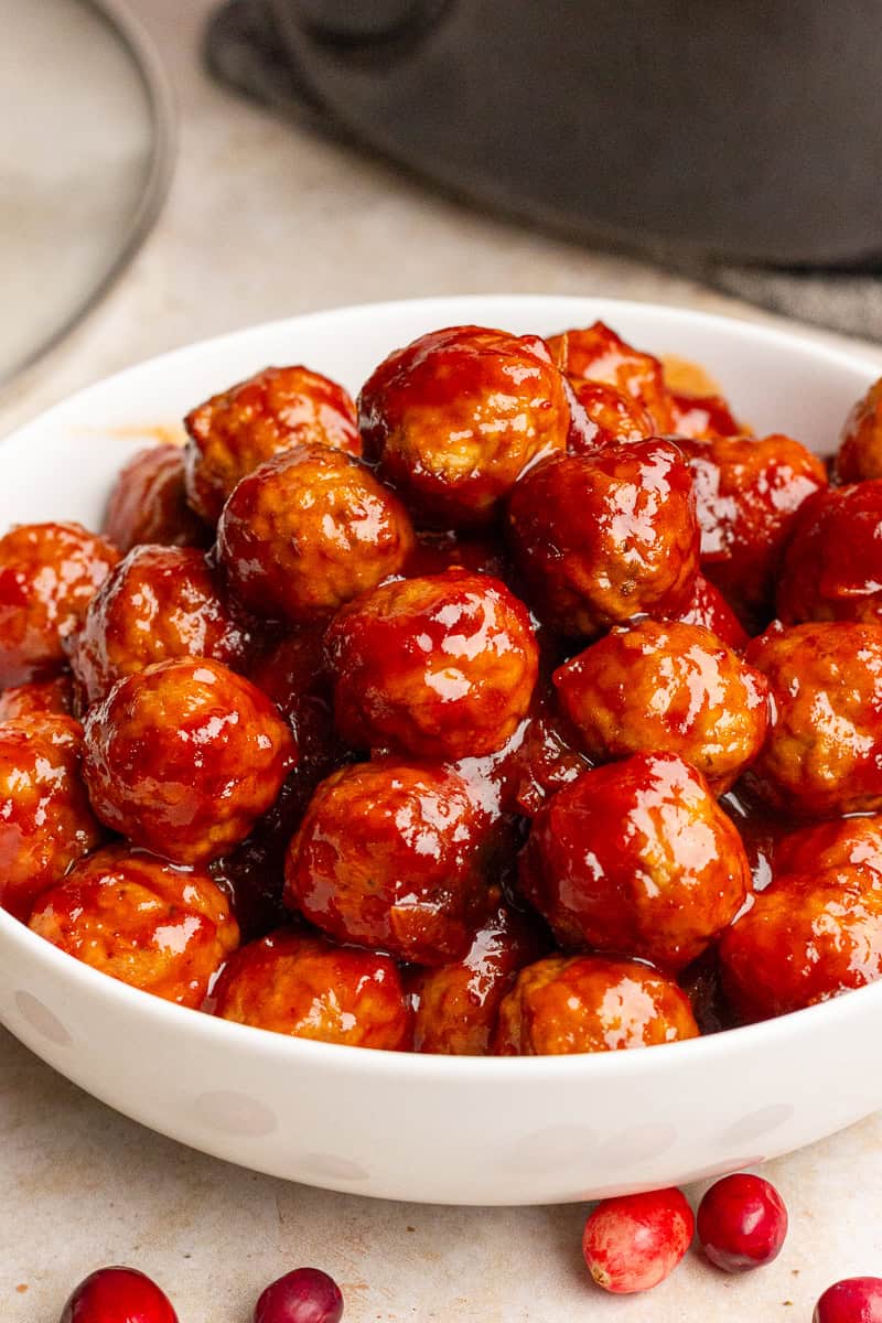 A white serving bowl piled high with cranberry barbecue meatballs.
