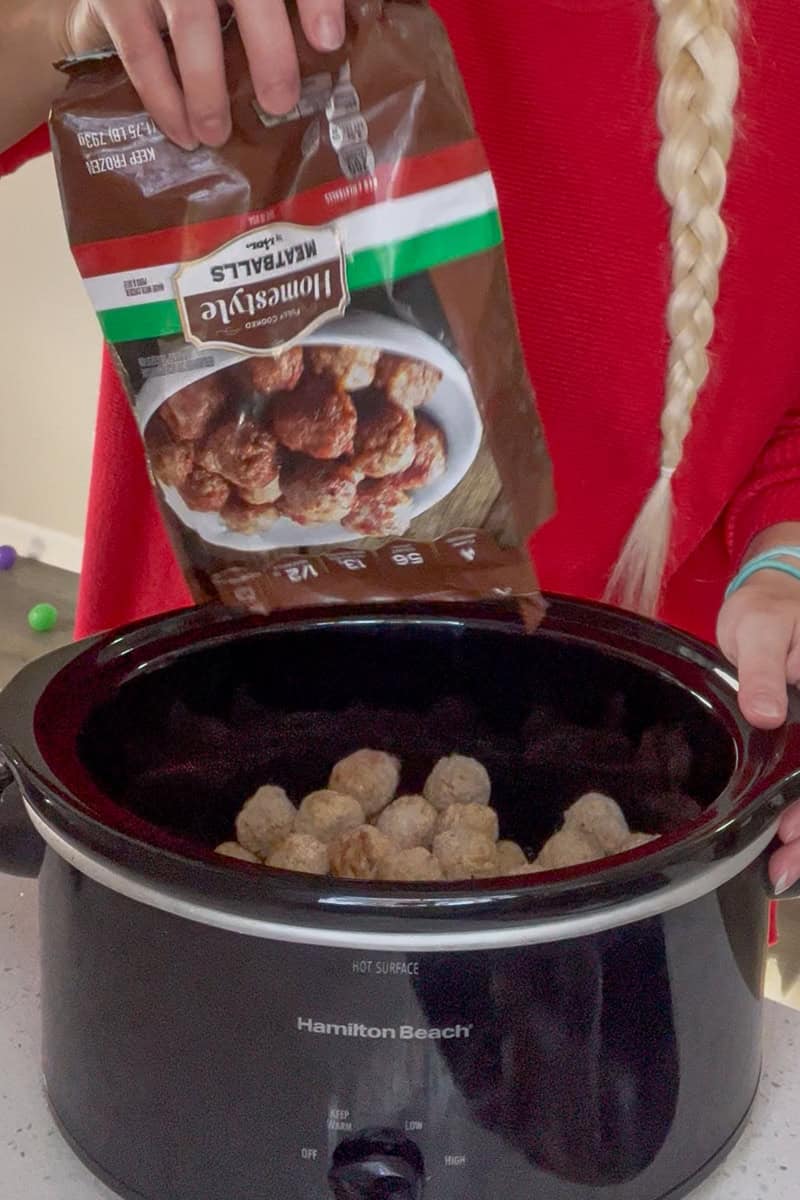 A bag of frozen meatballs being poured into a slow cooker at the start of the recipe.