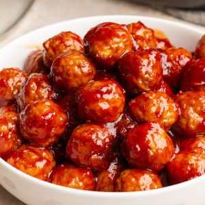 A close-up bowl full of glossy cranberry barbecue meatballs ready to serve.