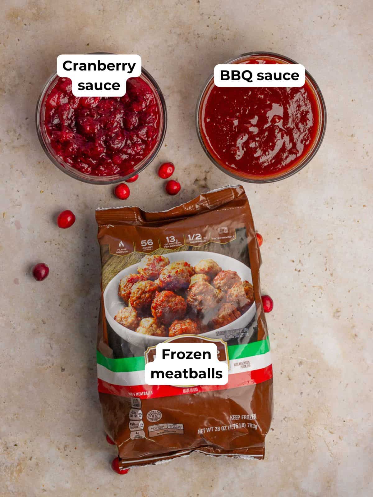 Frozen meatballs, cranberry sauce, and barbecue sauce arranged on a countertop as the recipe ingredients.