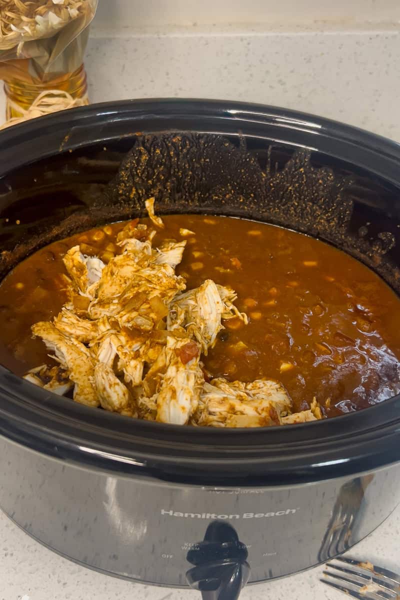 Shredded chicken added back into the slow cooker with enchilada sauce mixture.