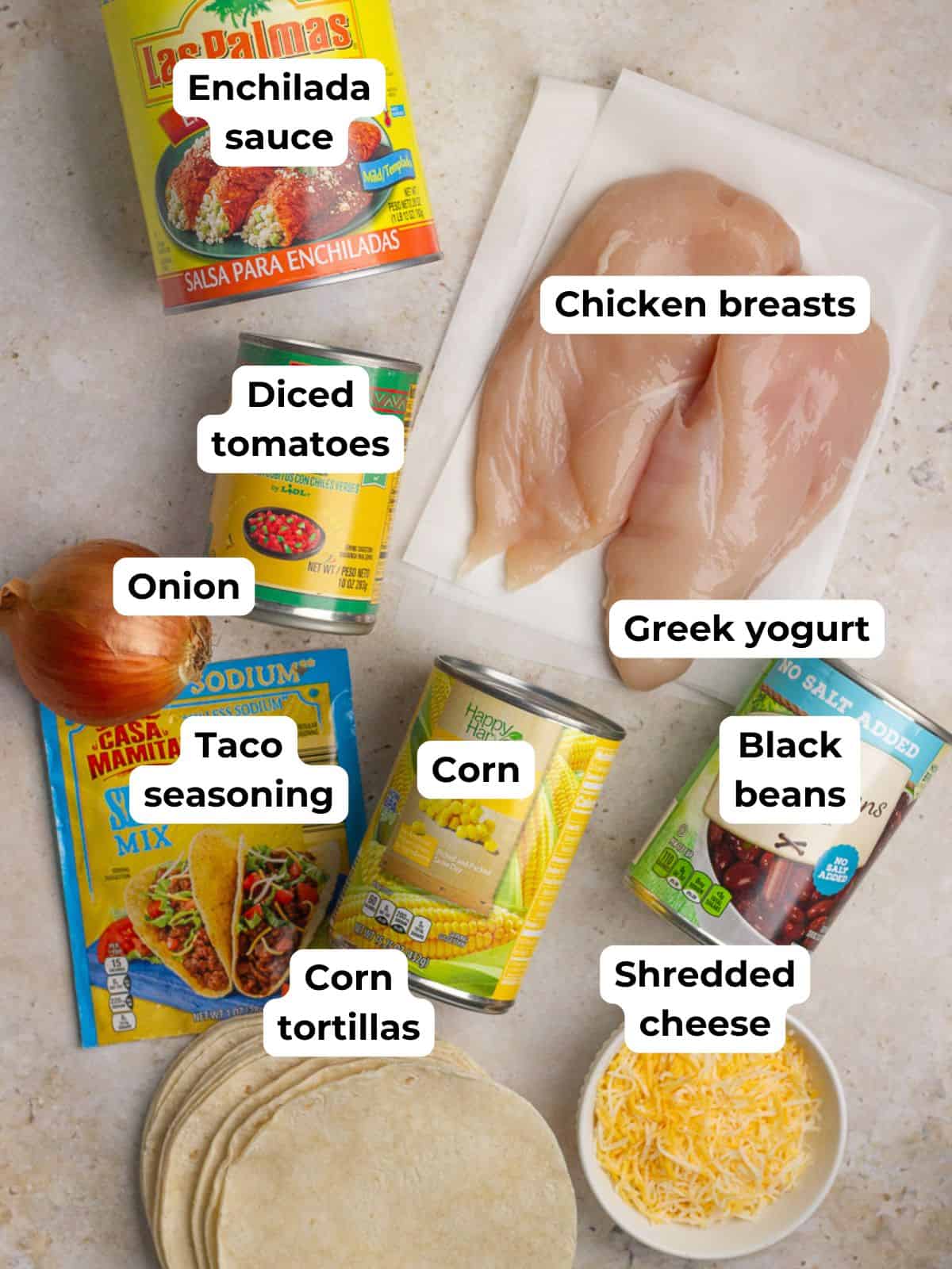 Overhead shot of ingredients for crockpot chicken enchilada casserole including chicken, enchilada sauce, beans, and tortillas.
