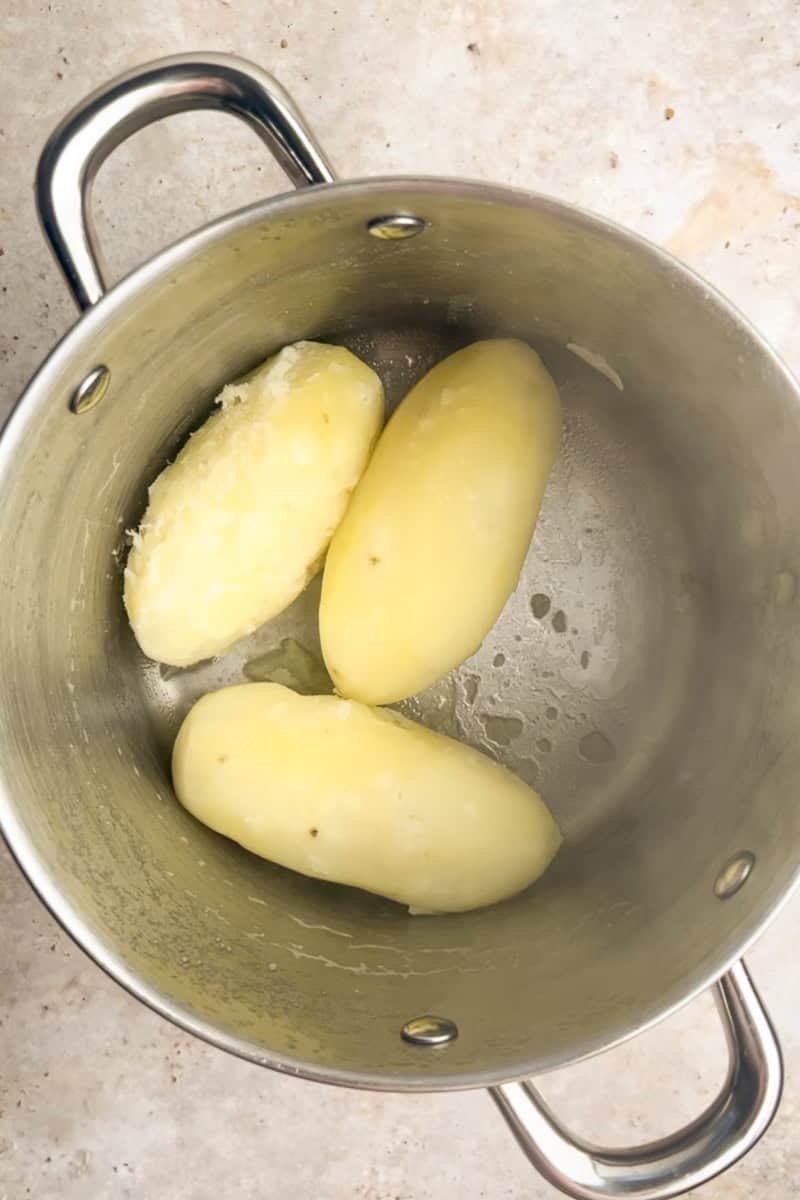 A pot of freshly boiled potatoes resting in the bottom of a stainless steel pot.