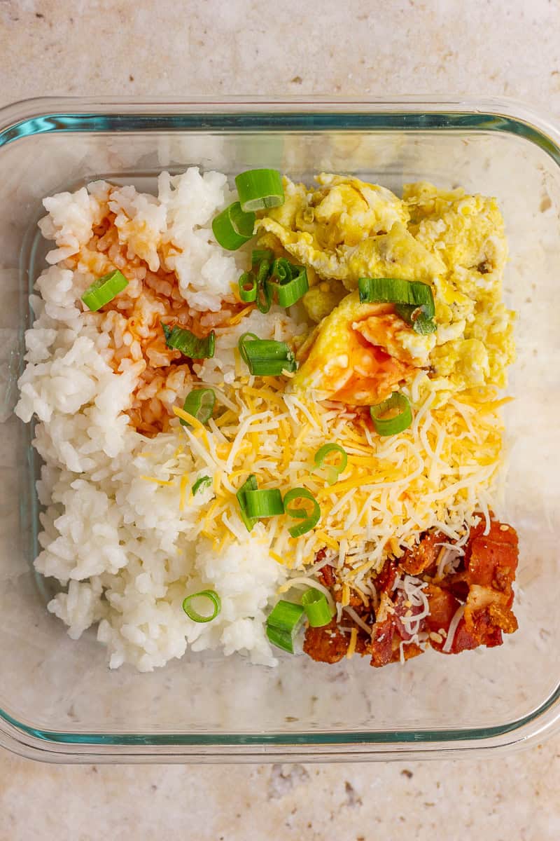 A classic Southern-style breakfast rice bowl with eggs, cheese, bacon, and hot sauxe over warm rice.
