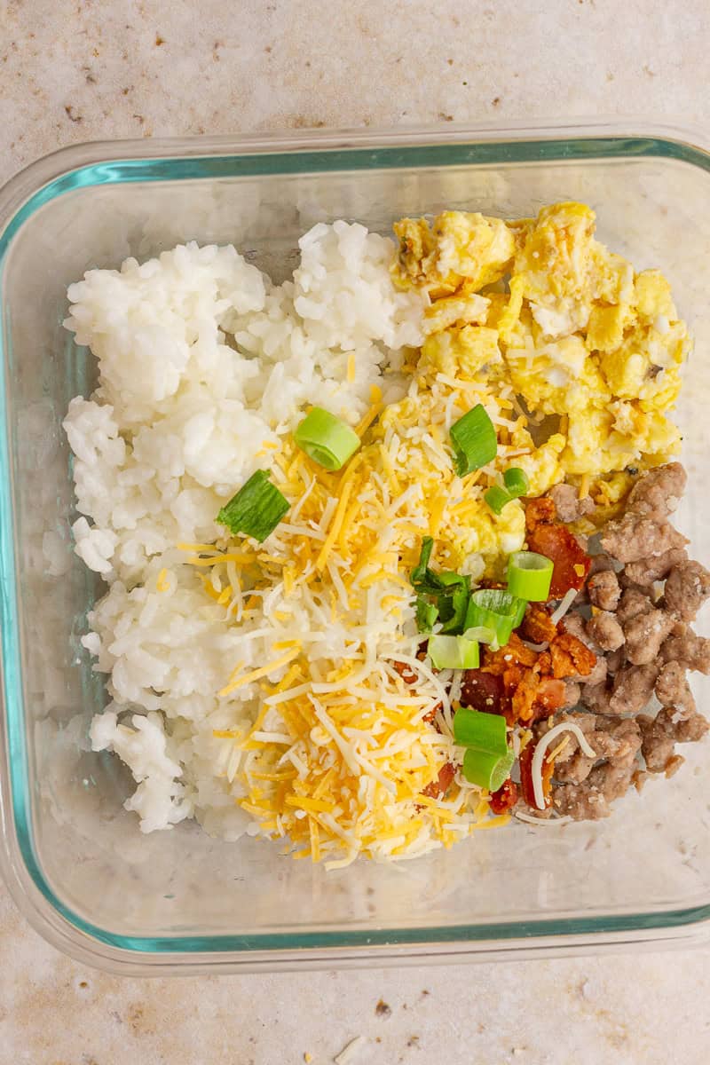A meat lover's breakfast rice bowl with bacon, turkey sausage, scrambled eggs, and cheese.