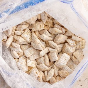 Finished cookie butter puppy chow cooling inside a zip-top bag with an even powdered coating.