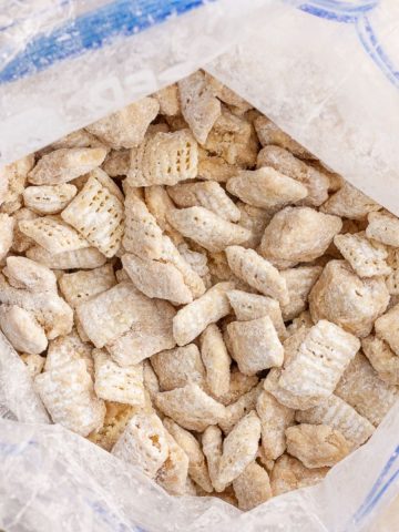 Finished cookie butter puppy chow cooling inside a zip-top bag with an even powdered coating.