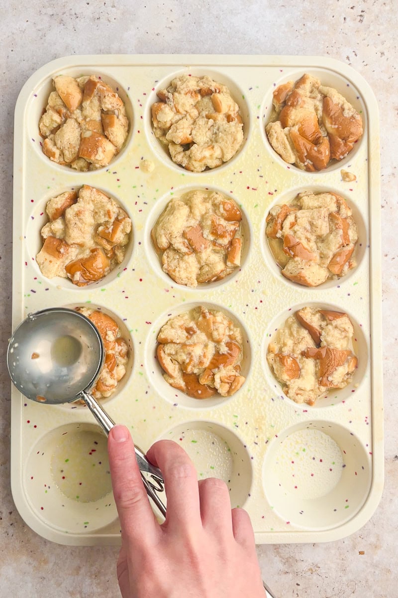 A muffin tin filled with scoops of soaked bread mixture pressed gently into each well.