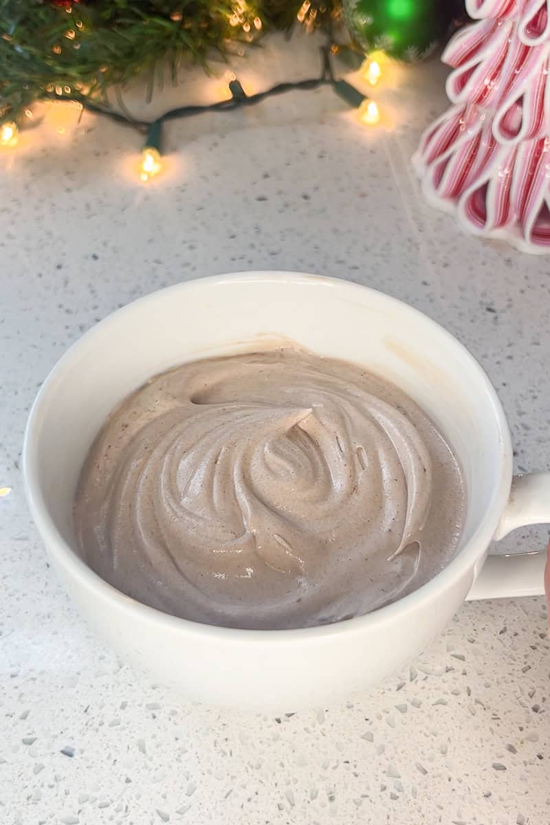 Smooth hot cocoa dip swirled in a white mug before adding toppings.