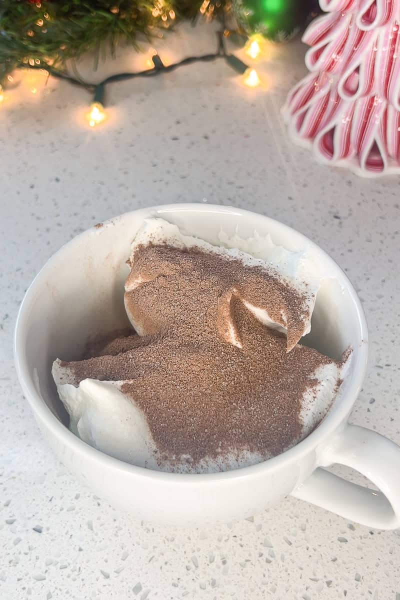 Hot cocoa mix sprinkled over Greek yogurt and whipped topping in a bowl before mixing.