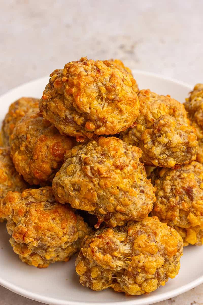 A close-up plate of golden brown sausage balls stacked together.