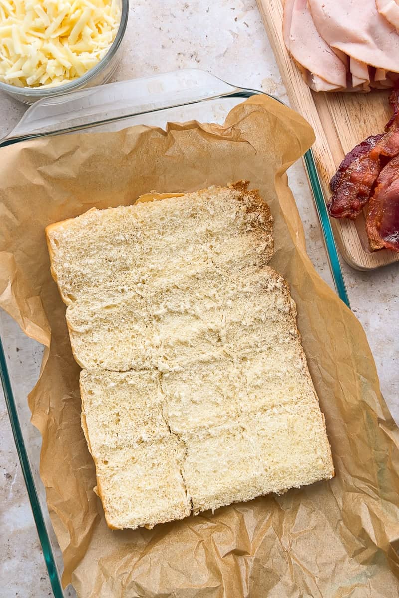 Hawaiian rolls sliced in half and placed in a baking dish to prepare hot brown sliders.