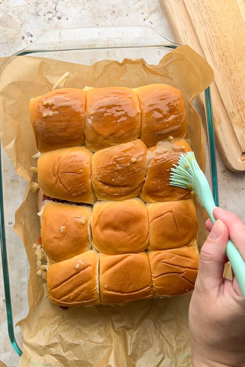 Butter mixture brushed over the tops of assembled Hawaiian roll sliders before baking.