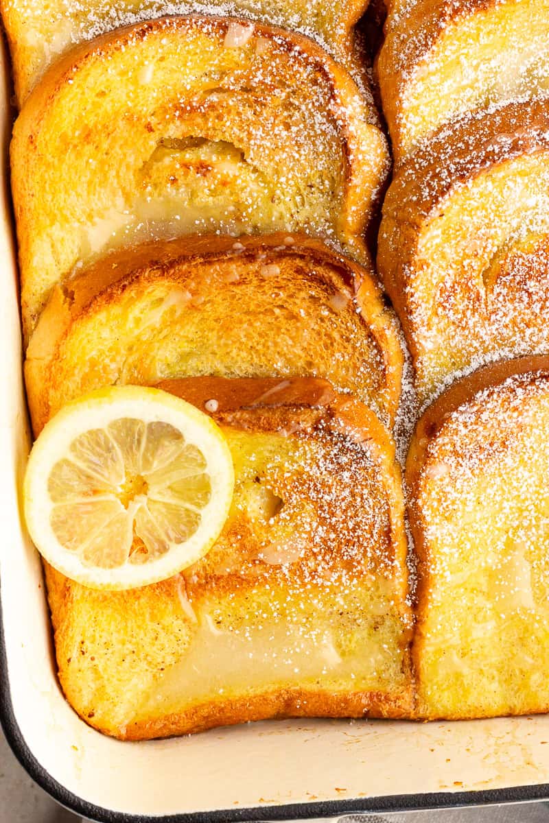 Close-up of baked lemon french toast with a soft center, golden edges, and light powdered sugar.